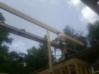 Carpenter setting a ridge beam over a new addition frame — Ice Dam Removal by Roofing Brothers in Alplaus