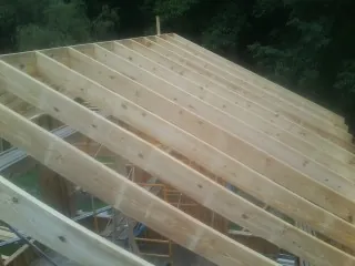 New roof rafters set over an addition before sheathing in Alplaus