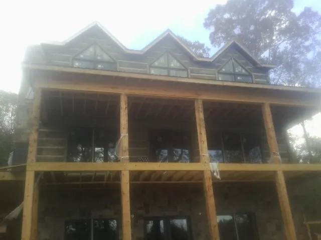 Dormers and porch framing on a large log home under construction — Roof Coating work by our crew in Alplaus