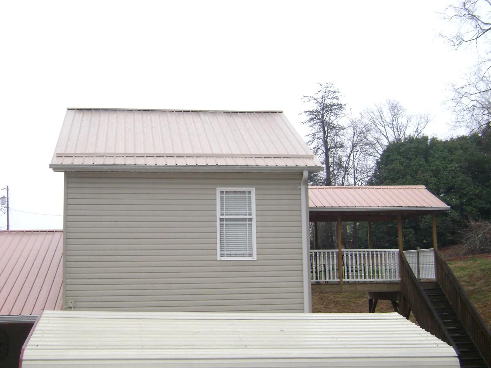 Tan metal roofs on a two story addition and attached porch, from a Roof Replacement job in Alplaus