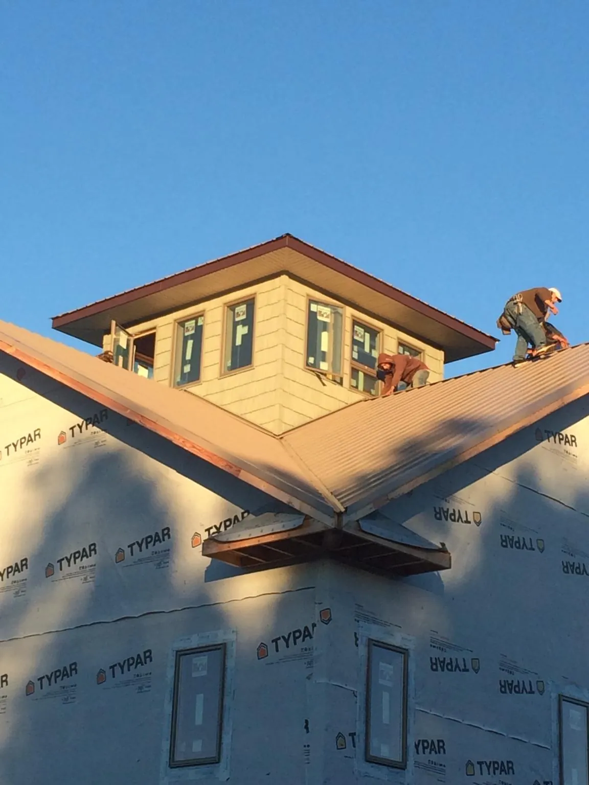 Roofers working around a rooftop cupola on a new metal roof at sunset — Roof Waterproofing in Alplaus by Roofing Brothers